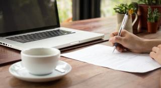 Hand schrijft op papier voor pc en koffietas